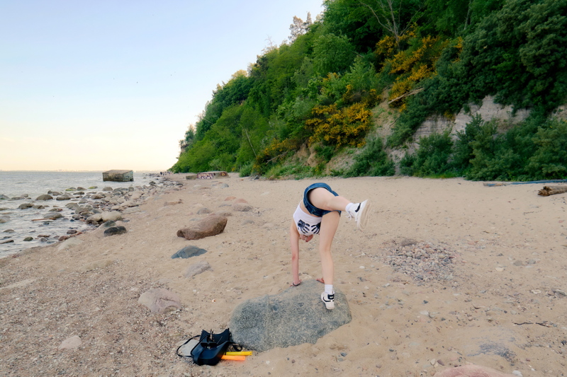 6 - A person doing a handstand on a large boulder along the sandy shore of the Klif Orłowski in Gdynia, Poland